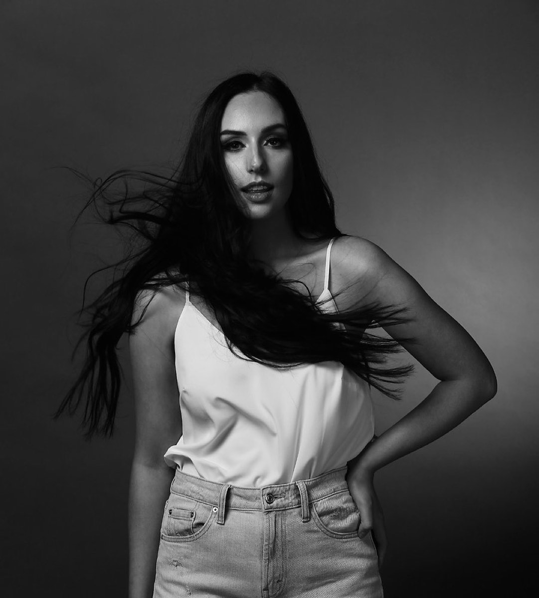 Long dark hair caught mid-movement in a black-and-white studio portrait